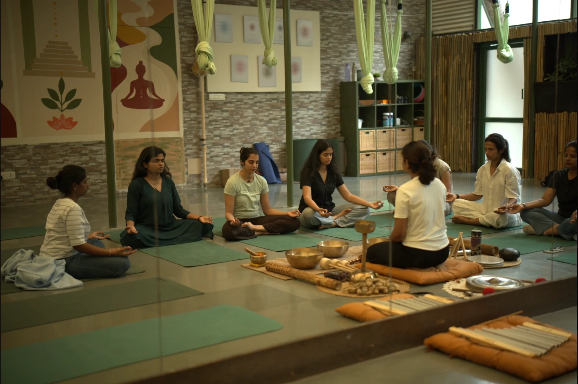 Women seated in meditation in a circle around a facilitator and singing bowls at The Sphere