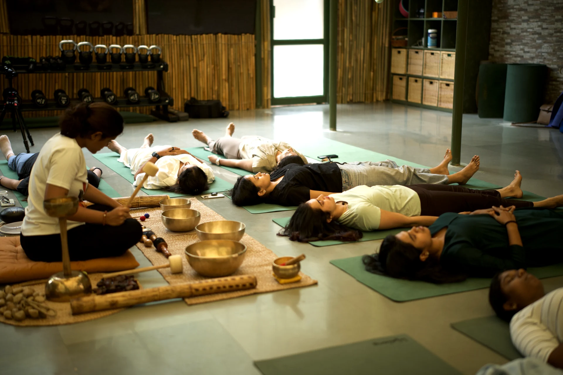 A Sphere facilitator playing singing bowls as women rest together